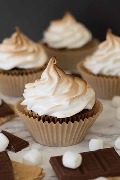 several cupcakes with white frosting and marshmallows