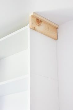 a white book shelf with two wooden shelves on each side and a light fixture above the bookshelf