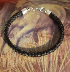 a black braided leather bracelet with silver clasp