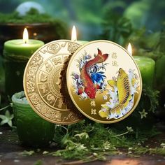 two gold coins sitting next to each other on top of green plants with candles in the background