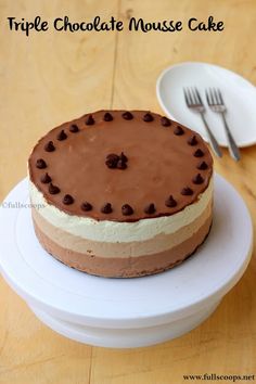 a triple chocolate mouse cake sitting on top of a white plate next to a fork