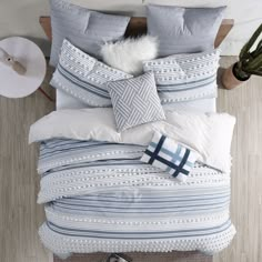 an aerial view of a bed with blue and white comforters, pillows and blankets