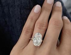 a woman's engagement ring with an oval cut diamond in the center, on her finger