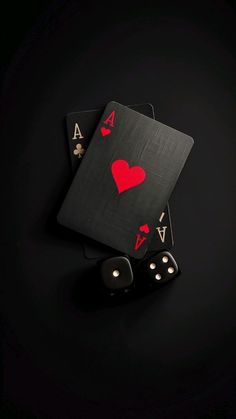 two playing cards and dice on a black surface with red heart cut out in the middle