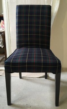 a black and blue plaid chair sitting in front of a white door with the seat up