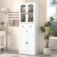 a tall white cabinet with glass doors in a bathroom next to a toilet and sink