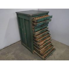 an old green cabinet with lots of wooden drawers on it's sides and one door open