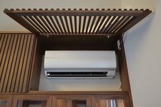 an air conditioner mounted to the side of a wooden cabinet in a room with white walls