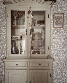 a white china cabinet with glass doors and drawers