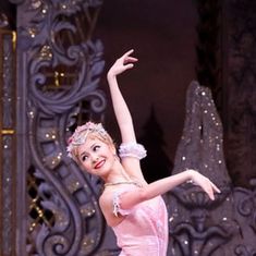 a young ballerina is posing for the camera with her arms in the air while wearing a pink dress