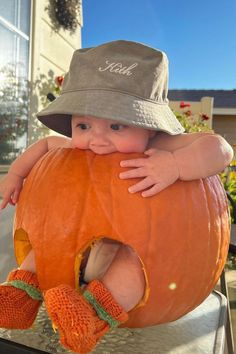 a baby in a hat and mittens is sitting on top of a large pumpkin