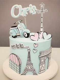 a blue cake decorated with the eiffel tower and paris on it's side