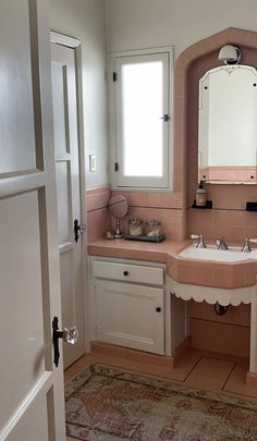 a bathroom with a sink, mirror and rug