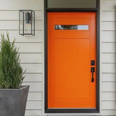 an orange front door with two planters on the side and one potted plant next to it