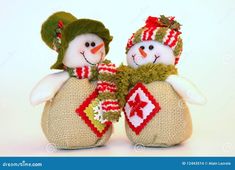 two snowmen in knitted hats and scarves sitting next to each other on a white background