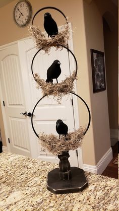 three black birds sitting on top of hay in a nest with a clock behind them