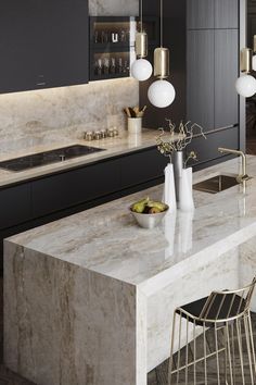 a modern kitchen with marble counter tops and gold accents on the cabinets, along with two vases filled with flowers