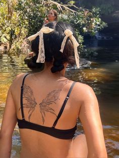 a woman with tattoos on her back standing in the water