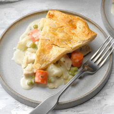 a white plate topped with chicken pot pie and veggies next to a fork