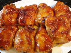 chicken wings covered in sauce on a white plate with black granite countertop behind it