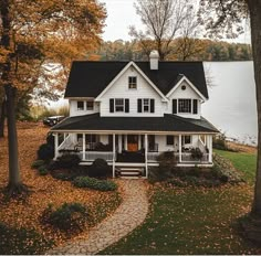 a large white house sitting on top of a lush green field next to a lake