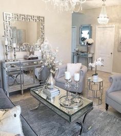 a living room filled with furniture and a chandelier above a glass coffee table