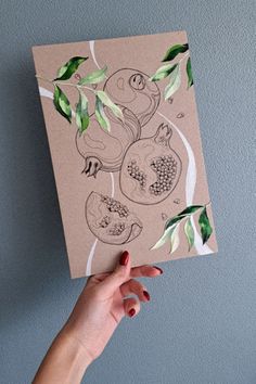 a hand holding up a piece of paper with drawings on it and leaves around the edges