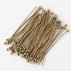 several brass colored pins and needles on a white surface