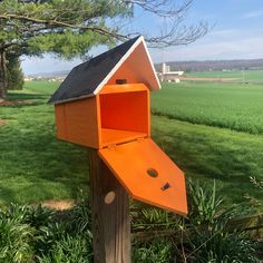 an orange bird house with a black roof