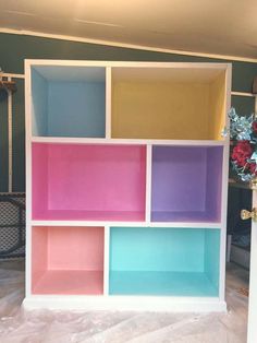 a multicolored book shelf with flowers in the corner and other items behind it