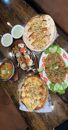 a table topped with lots of food on top of a wooden table covered in plates and bowls