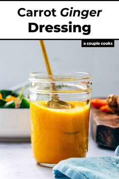 a jar filled with carrot ginger dressing next to a cutting board and blue napkins