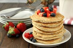 a stack of pancakes with strawberries and blueberries on top