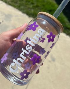 a hand holding a purple and white flowered tumbler with the name charlotte on it