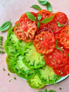 sliced tomatoes and lettuce on a plate with basil sprinkled on top