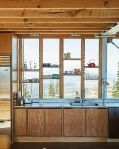 a kitchen with wooden cabinets and windows overlooking the mountain range is shown in this image