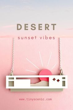 A laser cut house necklace with mountain and setting sun, on sterling silver chain. The necklace is set on a pink background and a photograph of a sunset sky. The words DESERT SUNSET VIBES are written in sage green and pink text. Southwestern Aesthetic, House Necklace, Gift For Architect, Modernist House, Desert Vibes, Desert Homes, Southwest Desert, Sunset View