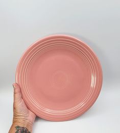 a person's hand holding a pink plate