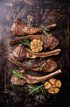 raw steaks with rosemary and garlic on an old wooden background