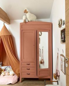 a pink armoire in a child's room with an animal on top of it