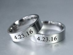 two wedding rings with the names of each couple engraved on them, sitting side by side