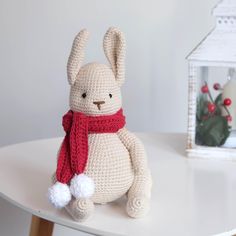 a crocheted bunny sitting on top of a table next to a small house