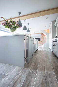 a kitchen with wooden floors and gray cabinets, an island countertop and hanging lights