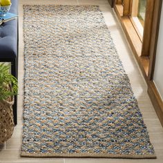 a blue and white rug on the floor next to a couch with a plant in it