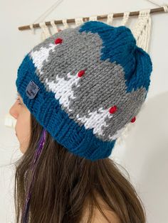 a woman wearing a blue and gray knitted hat with red buttons on the brim