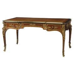 an antique style desk with gold trimmings and carvings on the top, sitting against a white background