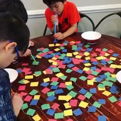 three boys are sitting at a table with colored post - it notes on the table