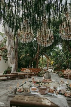 an outdoor dining area with chandeliers hanging from the ceiling and tables covered in flowers