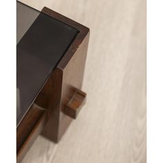 a close up view of a wooden table with black glass top and wood frame on the bottom