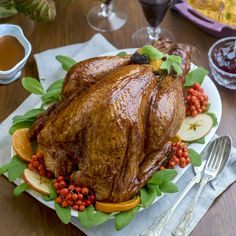 a roasted turkey on a platter with apples, oranges and cranberries